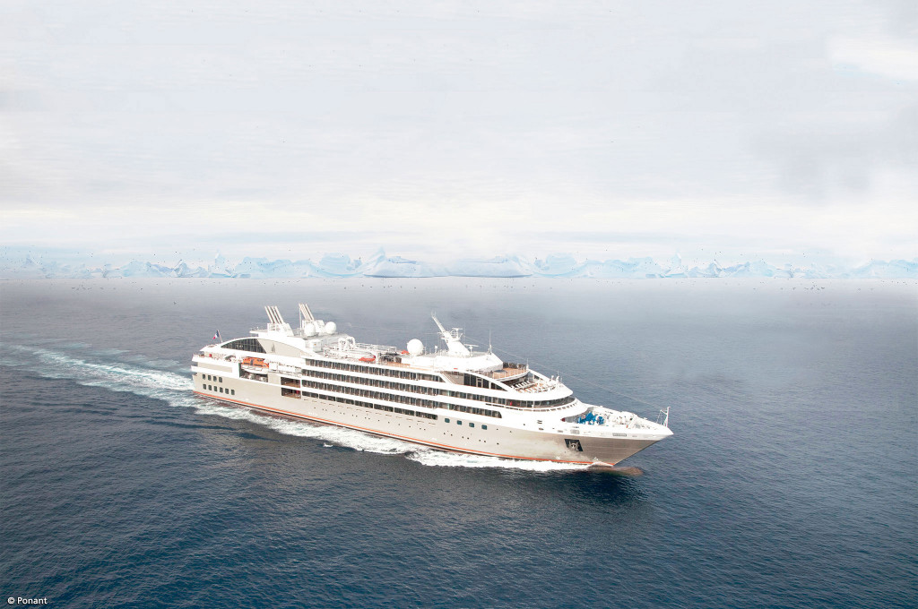 Le Soléal auf ruhigem Meer mit Eisbergen am Horizont in der Antarktis.