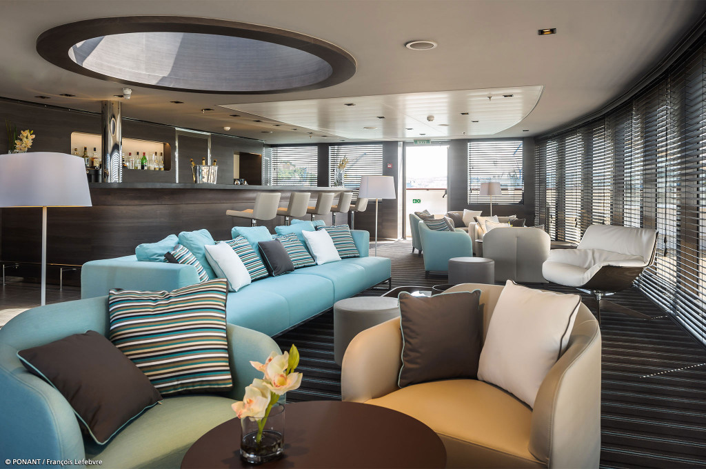 Lounge mit Barbereich, Sofas und Sesseln in warmen Farben an Bord der Le Soléal.