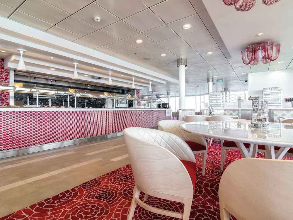Modernes Bufferestaurant in Weiß und Rot mit geschwungener Buffettheke, weißen Stühlen und rotem Blumenteppich