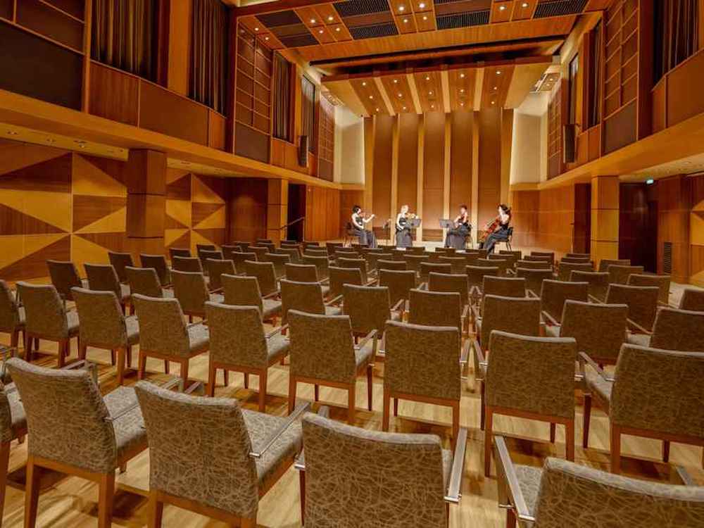 Klanghaus auf der Mein Schiff 3 mit warmem Holzdekor, Stuhlreihen und einem Streichquartett auf der Bühne