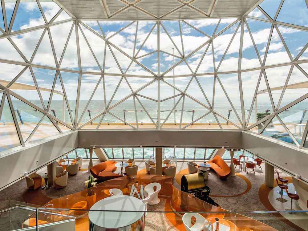 Moderne Café-Lounge mit großem Glasdach und Meerblick auf Flusskreuzfahrtschiff