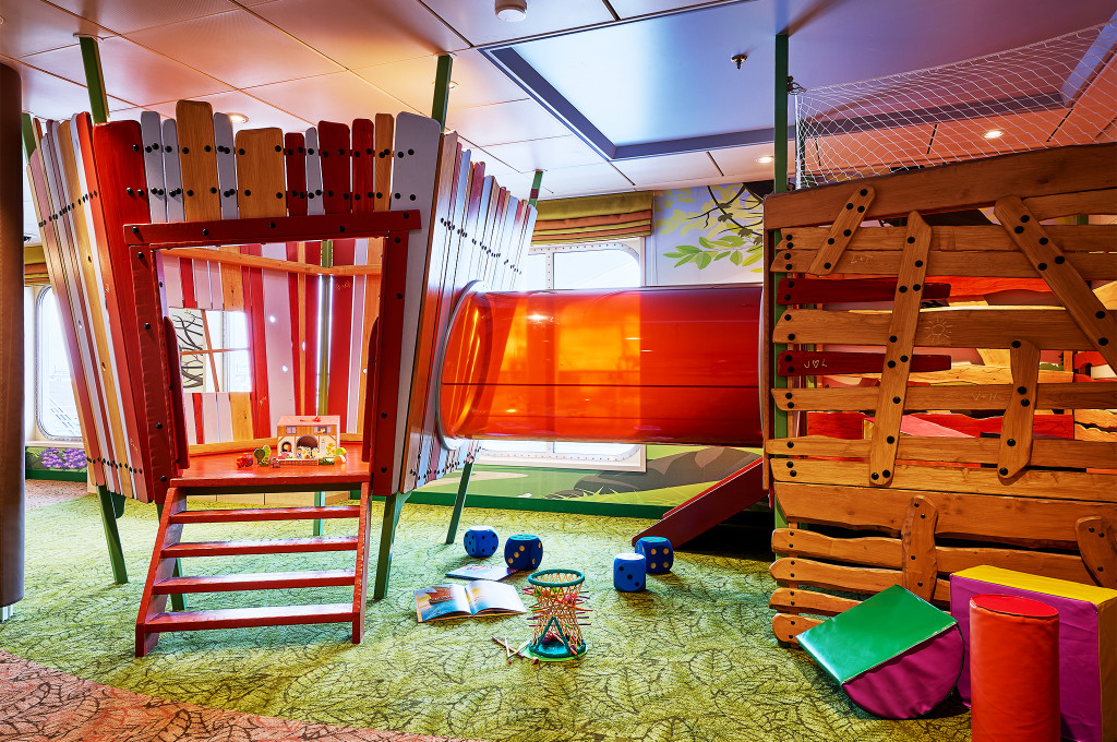 Kids-Club Insel der Seeräuber mit Holzburg, Rutsche und Klettergerüst auf grünem Teppichboden.