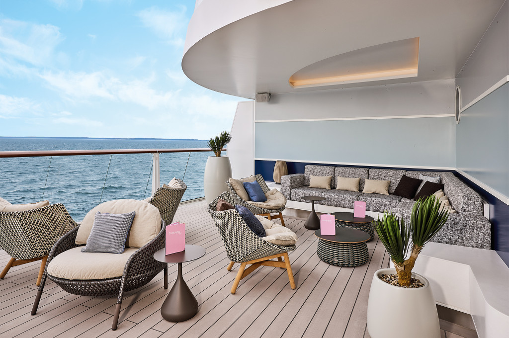 Loungebereich des Champagner Treffs mit Korbsesseln, Sofas und weitem Blick aufs Meer.