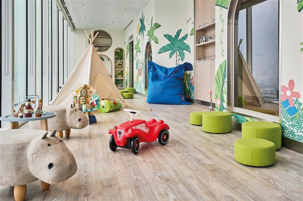 Babyraum Nest mit Tipi-Zelt, rotem Bobbycar, tierförmigen Hockern und kindgerechter Wandbemalung.