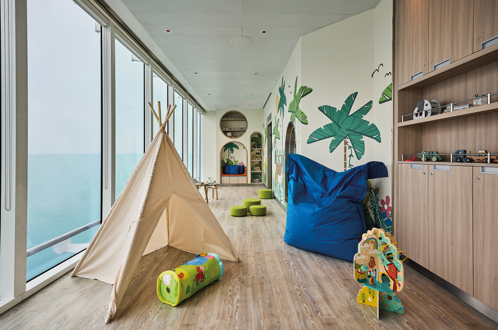 Babyraum Nest mit Tipi-Zelt, Sitzsack und dschungelthematischer Wandgestaltung vor Panoramafenstern.