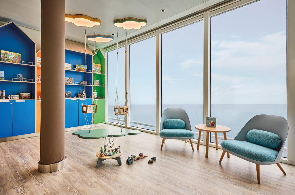 Leseecke im Nest Babyraum mit bunten Regalen, hängenden Schaukeln und Panoramablick aufs Meer.