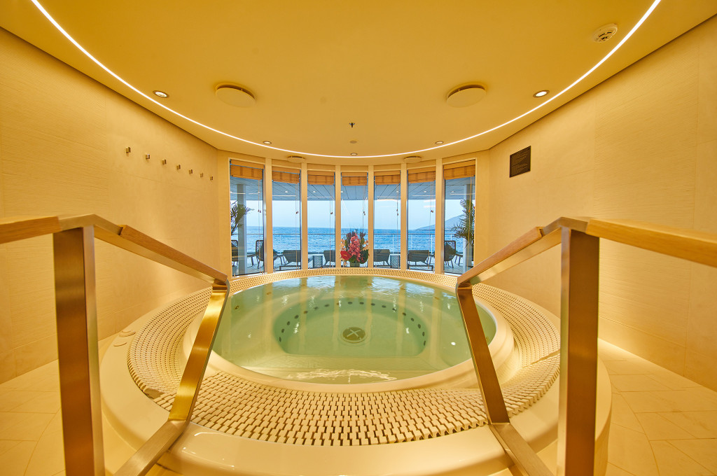 Runder Innen-Whirlpool im Ocean Spa der MS Europa 2 mit Panoramafenstern und Meerblick bei Abenddämmerung