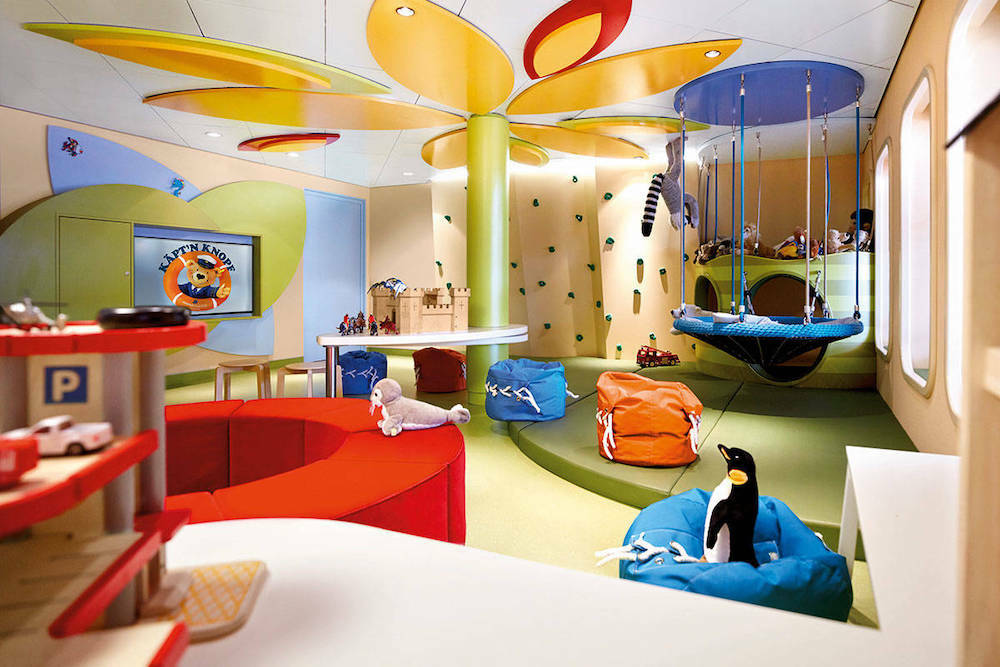 Bunter Kinderclub der MS Europa 2 mit Klettergerüst, Schaukeln und Spielzeug für Kinder.
