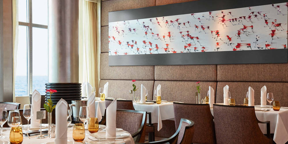 Restaurant Weltmeere auf der MS Europa 2 mit gedeckten Tischen, Polsterbänken, Flamingo-Kunstwerk und Panoramafenstern.