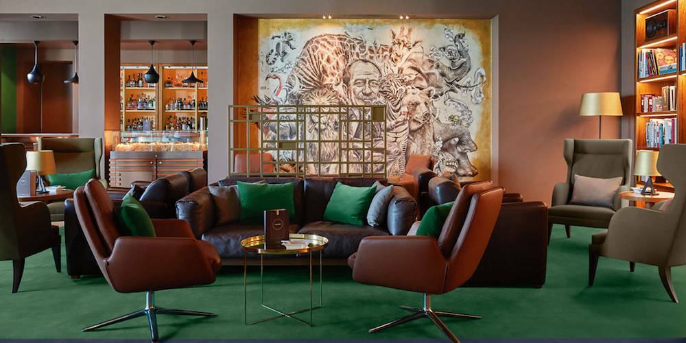 Bar Collins auf der MS Europa 2 mit ledernen Sesseln, großem Kunstgemälde und beleuchtetem Flaschenregal.