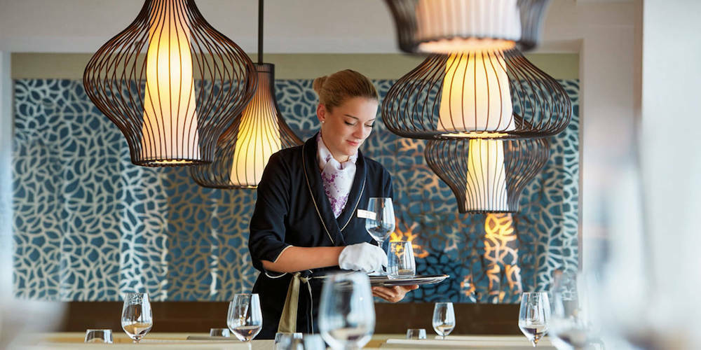 Servicemitarbeiterin deckt Tische im japanischen Sushi-Restaurant Sakura auf der MS Europa 2 ein.