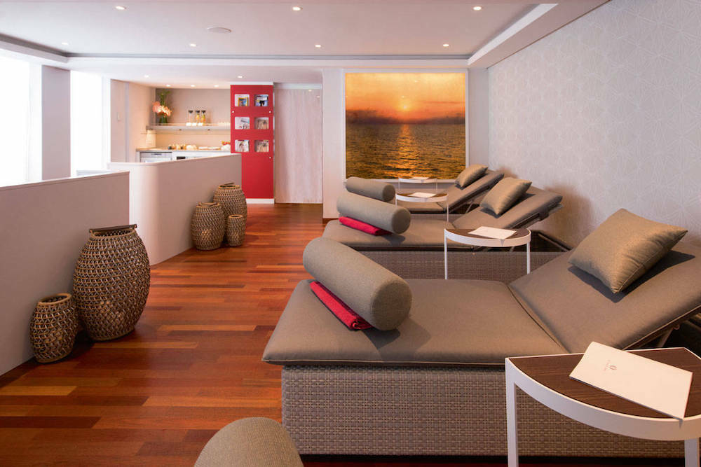 Ruhiger Spa-Ruheraum der MS Europa mit Liegestühlen und warmem Wandbild eines Sonnenuntergangs.