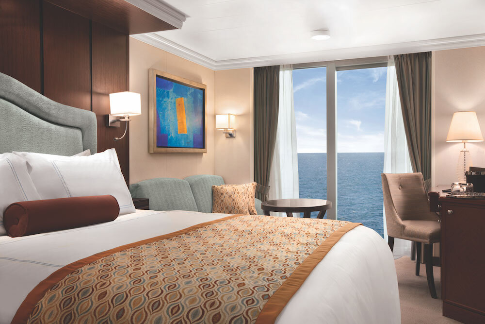 Klassische Balkonkabine mit Doppelbett, Sofa und großem Fenster mit Meerblick auf einem Hochseekreuzfahrtschiff
