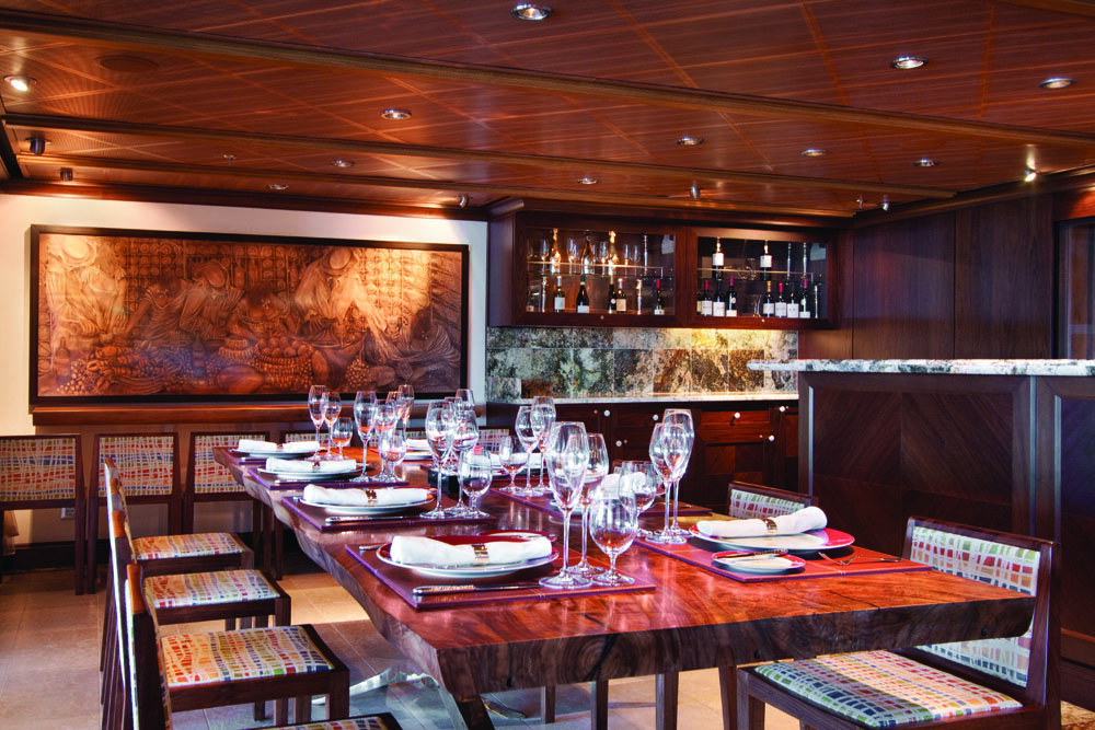 Privates Spezialitätenrestaurant mit langem Holztisch, Wandrelief und beleuchteter Weinbar unter Holzdecke