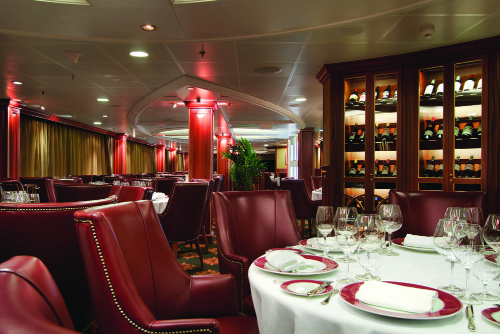 Elegantes Spezialitätenrestaurant mit burgunderroten Ledersesseln, eingedeckten Tischen und beleuchteten Weinschränken