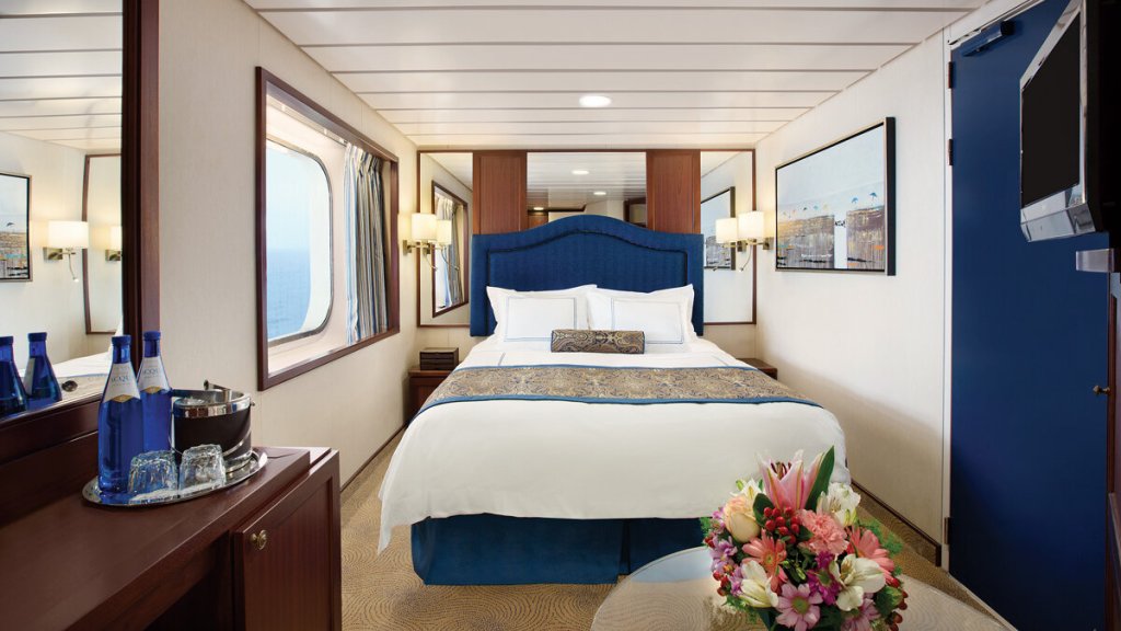 Deluxe Außenkabine der MS Nautica mit Panoramafenster, Doppelbett und elegantem Holzinterieur.