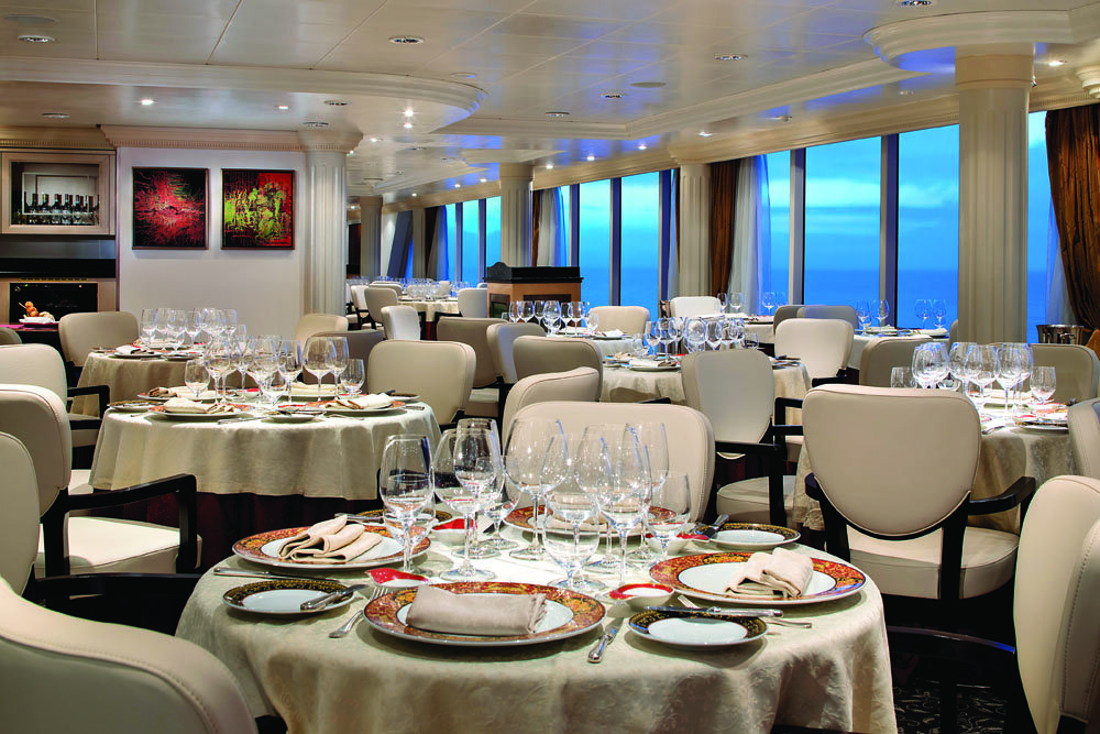 Elegantes Spezialitätenrestaurant mit festlich gedeckten Tischen und Panoramafenstern mit Meerblick
