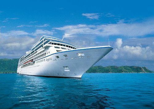 MS Nautica in tropischen Gewässern vor grüner Küste, Bugansicht des eleganten Luxuskreuzfahrtschiffes.