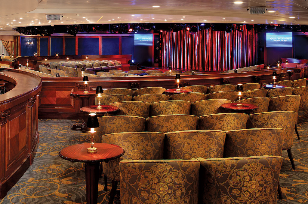 Show-Lounge mit Bühne, rotem Vorhang und gepolsterten Sitzreihen auf der Ms Nautica.