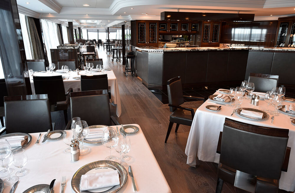Klassisches Spezialitätenrestaurant mit gedeckten Tischen und offener Theke im Hintergrund