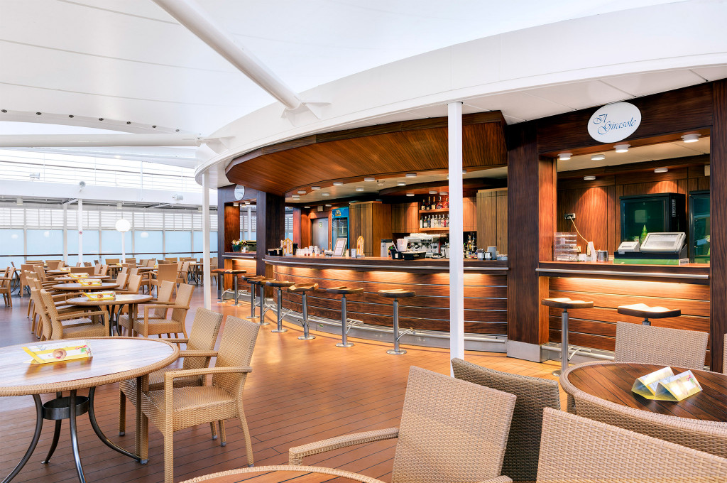 Außenrestaurant mit Bar, Rattan-Mobiliar und Holzdeck auf einem Kreuzfahrtschiff