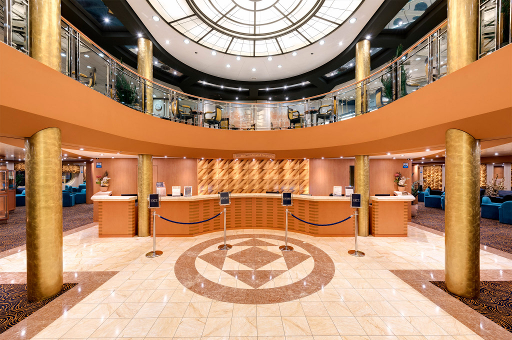 Prächtige Empfangshalle mit goldenen Säulen, Marmorboden und Glaskuppel auf einem Kreuzfahrtschiff