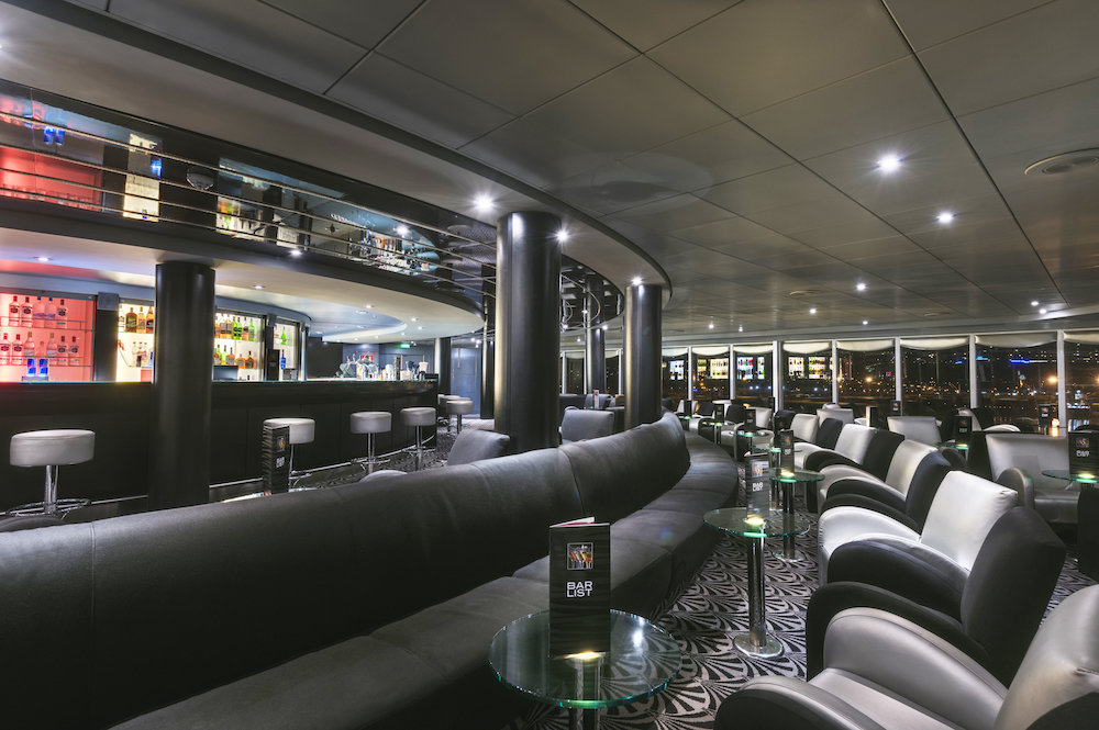 Diskothek Starlight Club der MSC Armonia mit dunklem Ledersofa, beleuchtetem Bartresen und Blick auf nächtliche Hafenlichter