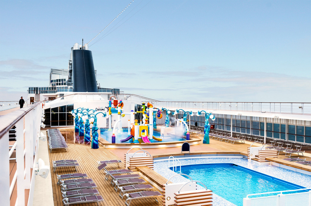 Pooldeck mit Außenpool, buntem Kinderwasserbereich und Liegestühlen auf einem Kreuzfahrtschiff