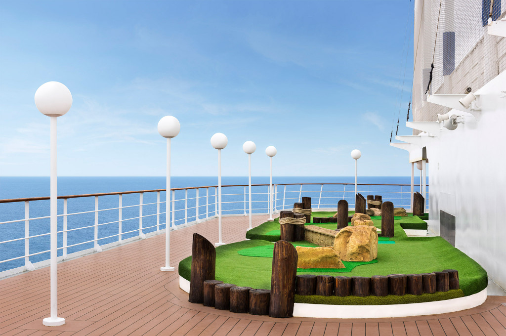 Minigolfplatz auf dem Sonnendeck mit Holzhindernissen, Reling und Meeresblick auf einem Kreuzfahrtschiff
