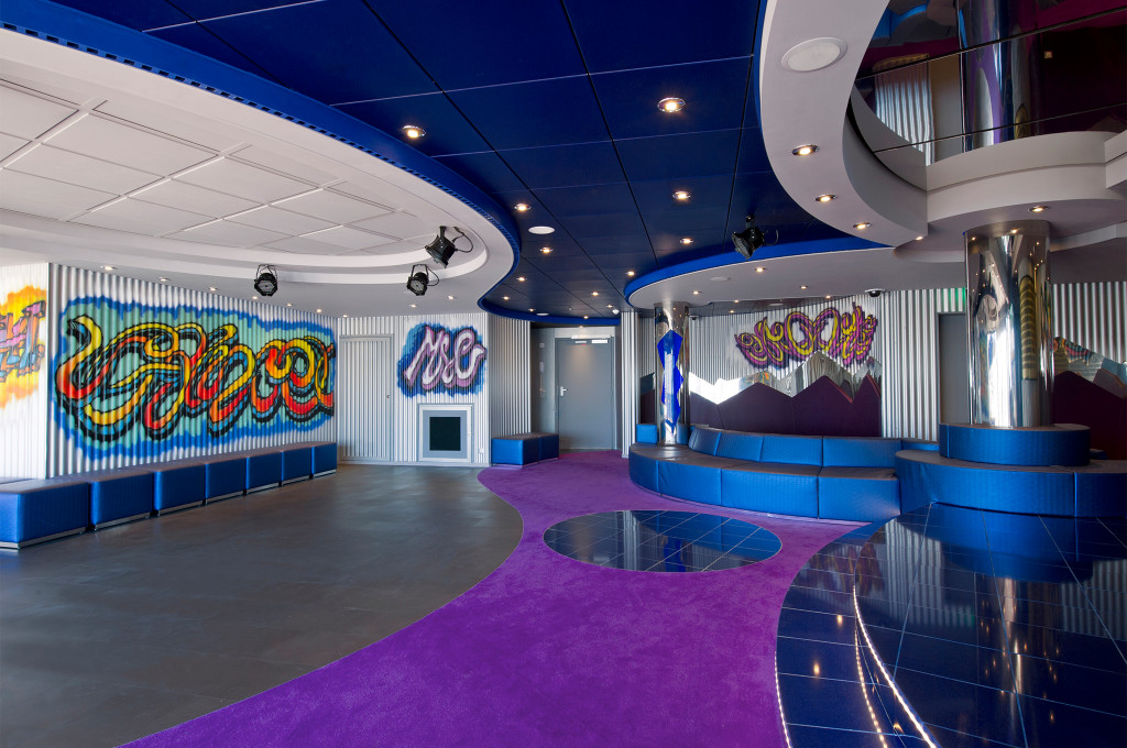 Teenclub mit bunten Graffiti-Wandmalereien, Tanzfläche, violettem Teppich und blauer Lounge-Bestuhlung