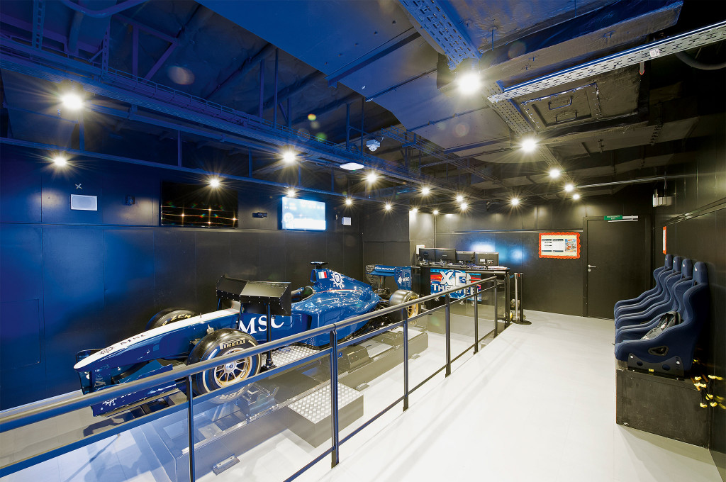 Simulator-Raum mit blauem Formel-1-Rennwagen und Fahrsimulator-Sitzen für interaktive Rennerlebnisse an Bord