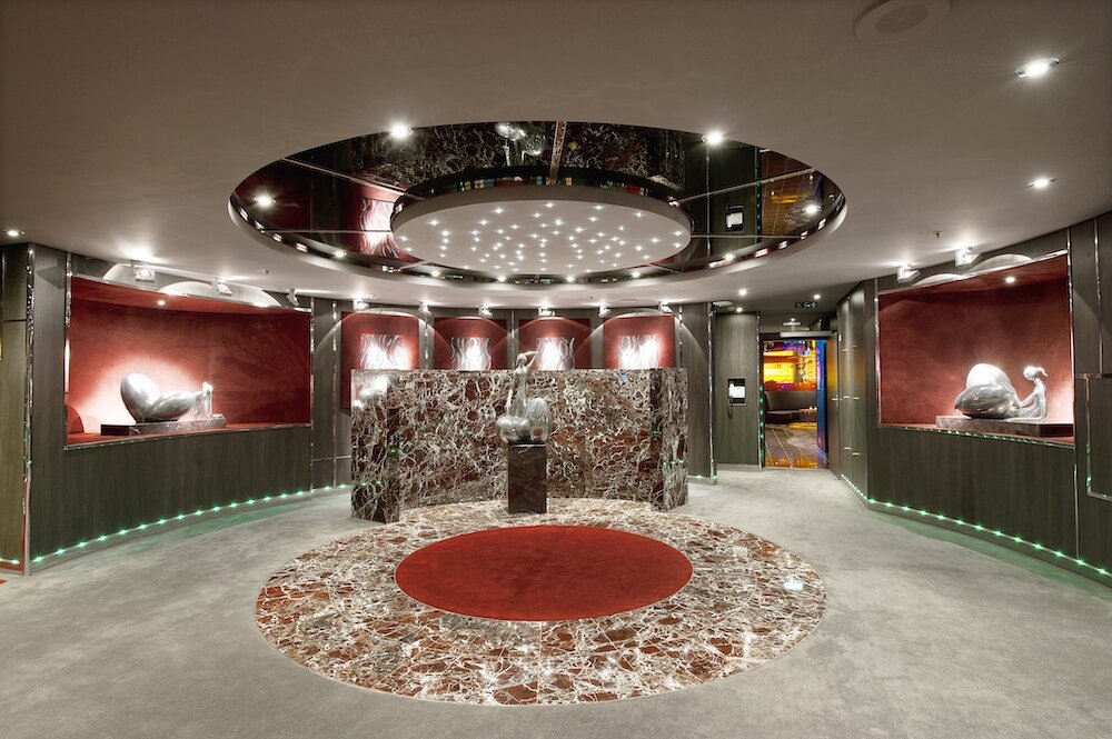 Kunstgalerie auf der MSC Divina mit rundem Marmoreinleger, beleuchteten Skulpturnischen und Spiegeldecke