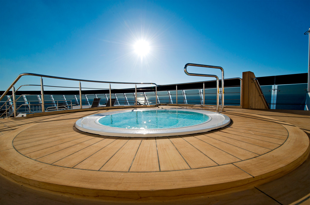 Runder Whirlpool auf dem Teakholz-Außendeck bei strahlendem Sonnenschein mit freiem Meerblick