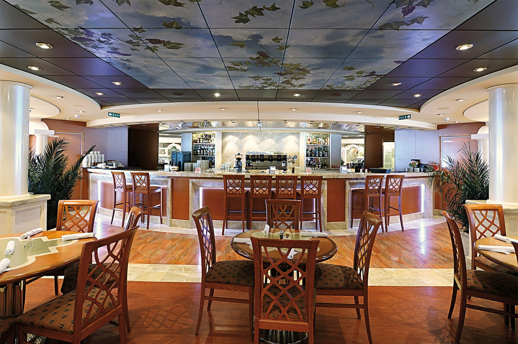 Bar-Restaurant auf einem Kreuzfahrtschiff mit langer beleuchteter Theke, Holzbarhockern und kunstvollem Weinreben-Deckengemälde