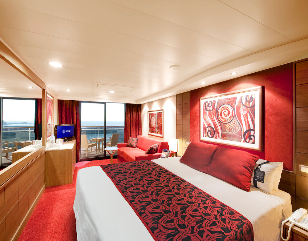 Premium Suite mit roter Designwand, komfortablem Bett und Meerblick.
