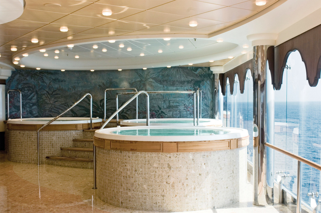 Whirlpool-Bereich im Spa eines Kreuzfahrtschiffes mit zwei runden Jacuzzis, Mosaikfliesen und tropischem Wandgemälde