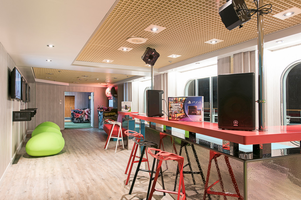Teen Club der MSC Sinfonia mit PlayStation-Station, DJ-Anlage, roten Stehtischen und grünen Sitzsäcken