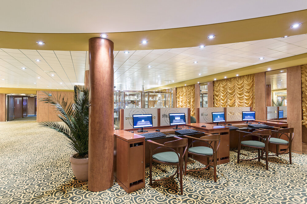 Internetcafé mit mehreren Computerarbeitsplätzen, Bronzesäule, Palme und ornamentalem Teppich