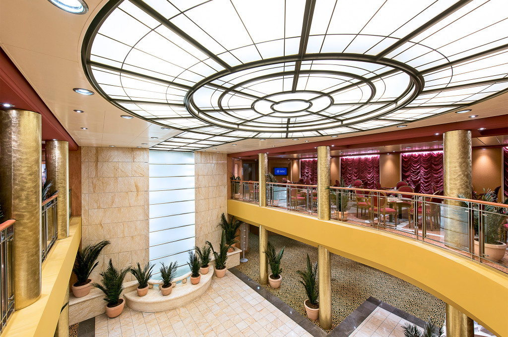 Zweistöckiges Atrium der MSC Sinfonia mit goldener Decke, Pflanzen, Kompassrose und Galeriebalkon