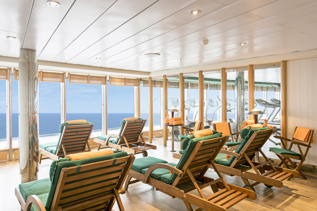 Spa-Ruhebereich der MSC Sinfonia mit Holzliegestühlen, grünen Polstern und Meerblick durch Panoramafenster