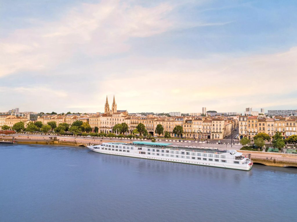 Flusskreuzfahrtschiff liegt an der Uferpromenade von Bordeaux an der Garonne vor der Altstadtkulisse.