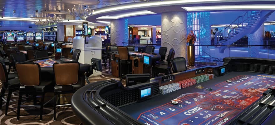 Geräumiges Casino mit Craps-Spieltisch, Roulette und Spielautomaten auf einem Kreuzfahrtschiff