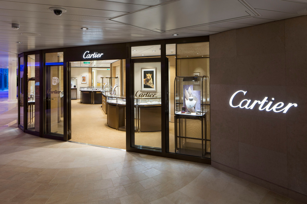 Cartier Boutique mit beleuchtetem Logo und Schmuckvitrinen im Einkaufsbereich an Bord der Ovation of the Seas.