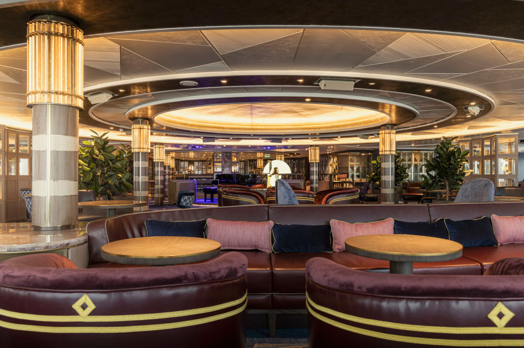 Commodore Club auf der Queen Anne mit großzügigem Loungebereich, runden Ledersofas und eleganten Säulen.