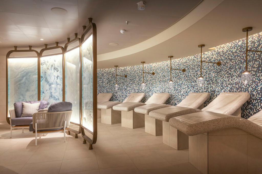 Spa-Ruhebereich mit beheizten Mosaikliegen, beleuchteter Onyxwand und Sitzecke auf einem Kreuzfahrtschiff