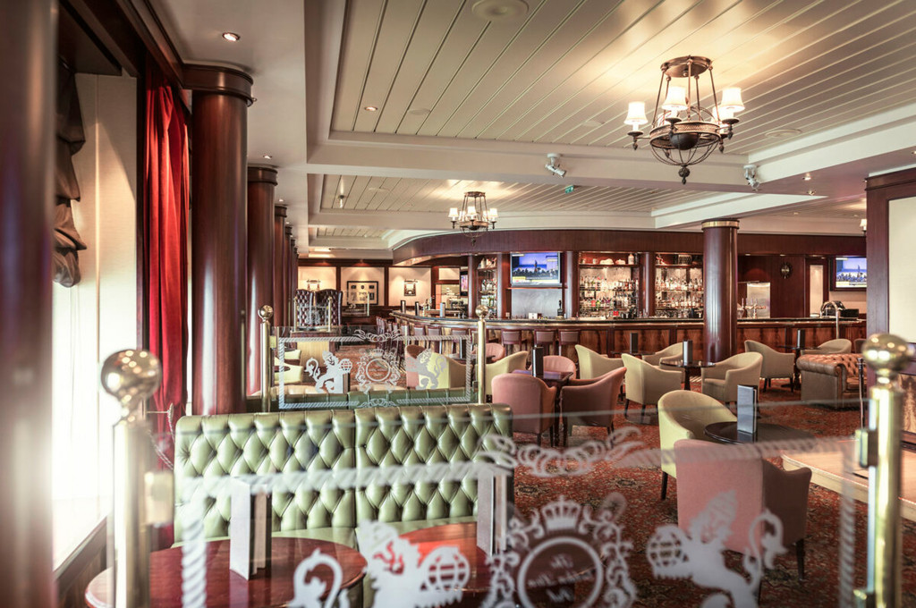 Britischer Pub Golden Lion der Queen Mary 2 mit grünem Ledersofa, Holzvertäfelung und Wappendeko