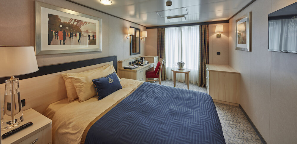 Außenkabine zur Alleinbenutzung auf der Queen Victoria mit Doppelbett, großem Fenster und Schreibtisch.