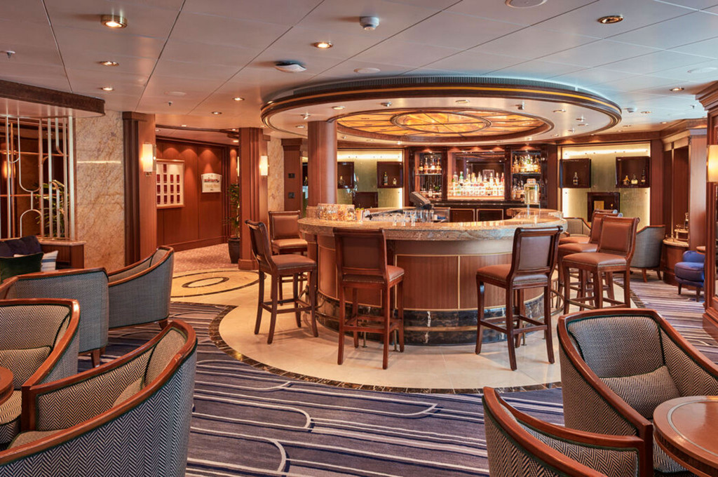 Chart Room Bar der Queen Victoria mit rundem Holztresen, Lederbarsesseln und warmem Ambiente