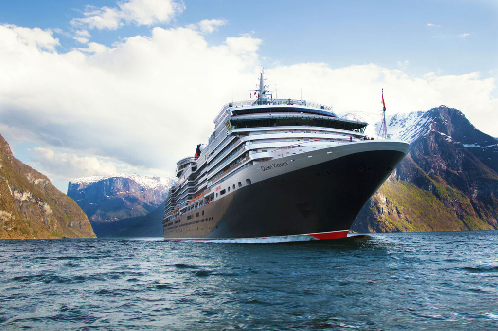 Kreuzfahrtschiff Queen Victoria fährt in einem norwegischen Fjord mit schneebedeckten Bergen im Hintergrund