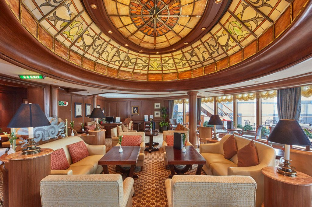 Grills Lounge der Queen Victoria mit prächtiger Tiffany-Glasdeckenkuppel und Sesseln in Creme und Lachs